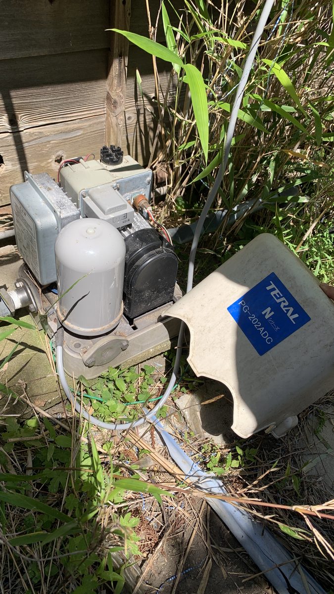 草に埋もれた井戸ポンプ。カバーを外したTERAL PG-202ADC。